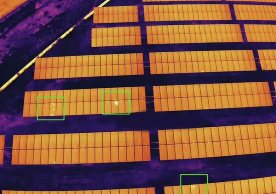 Thermal drone image of a solar farm with overheating panels outlined in green boxes